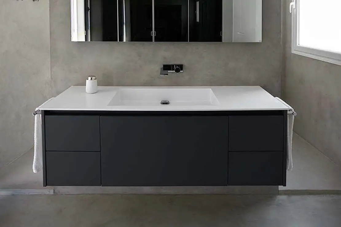 Baño de microcemento con piso, muros y regadera de tonalidad gris.